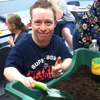 a man potting plants indoors at an HMEA Day Habilitation program