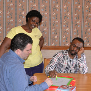 2 HMEA staff playing a game with a man supported by HMEA's residential program