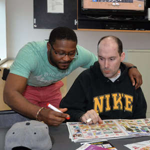 A man being assisted by a male HMEA staff person with an activity